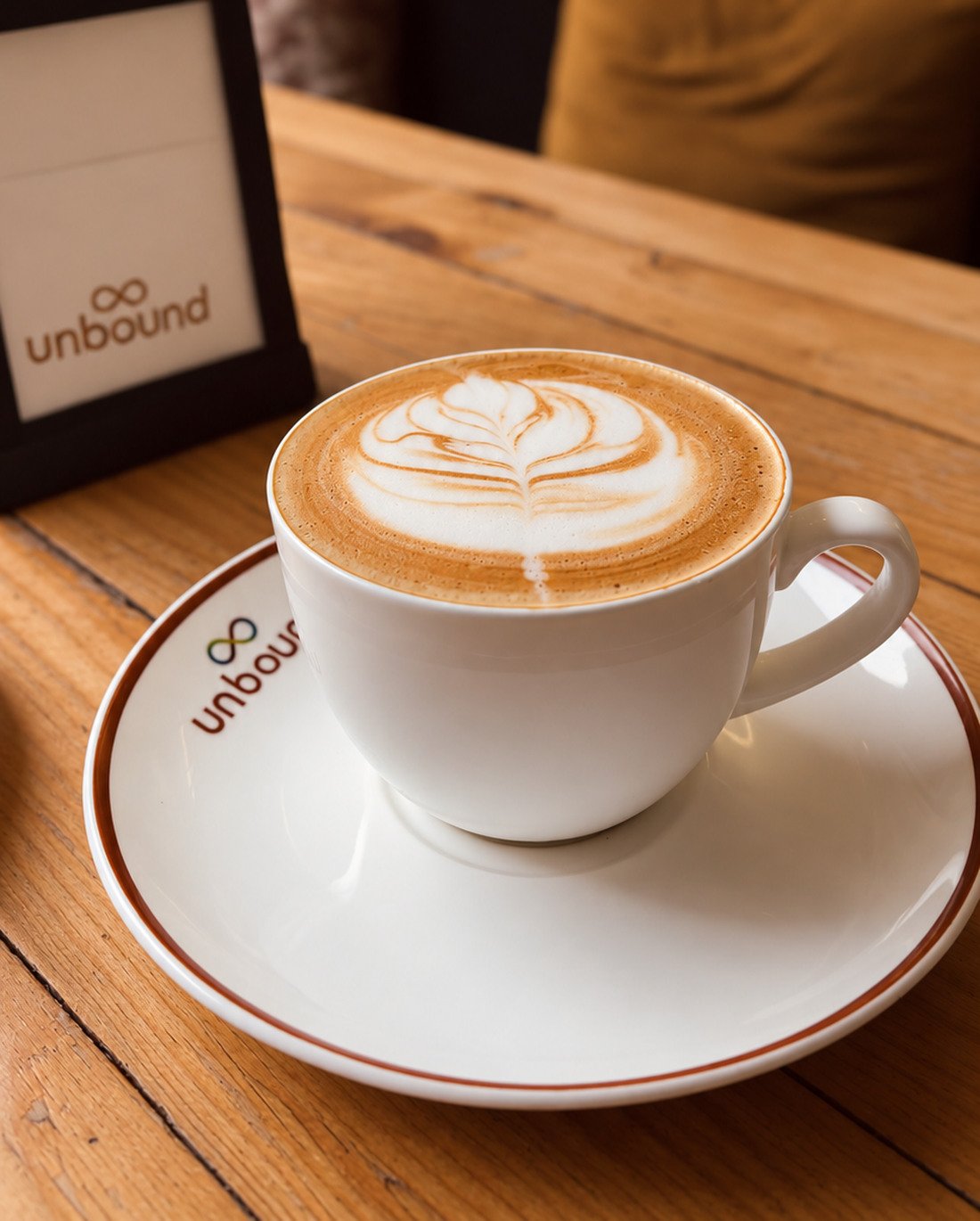 A cappuccino with leaf art on a wooden table