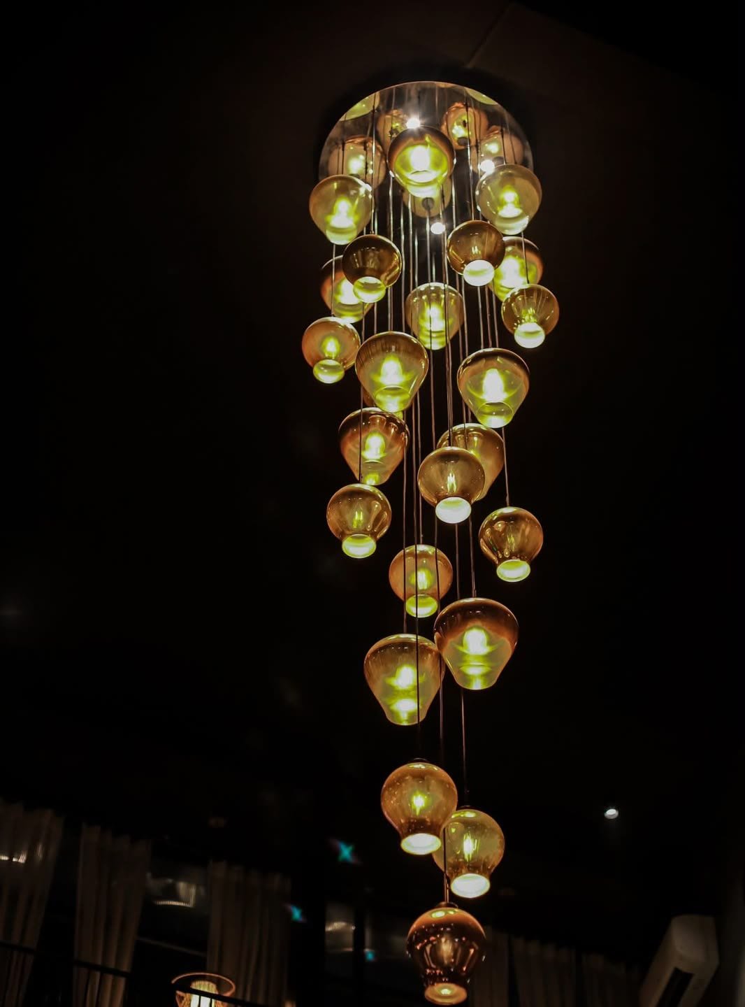The cascade of glass lamps over the dining room at night