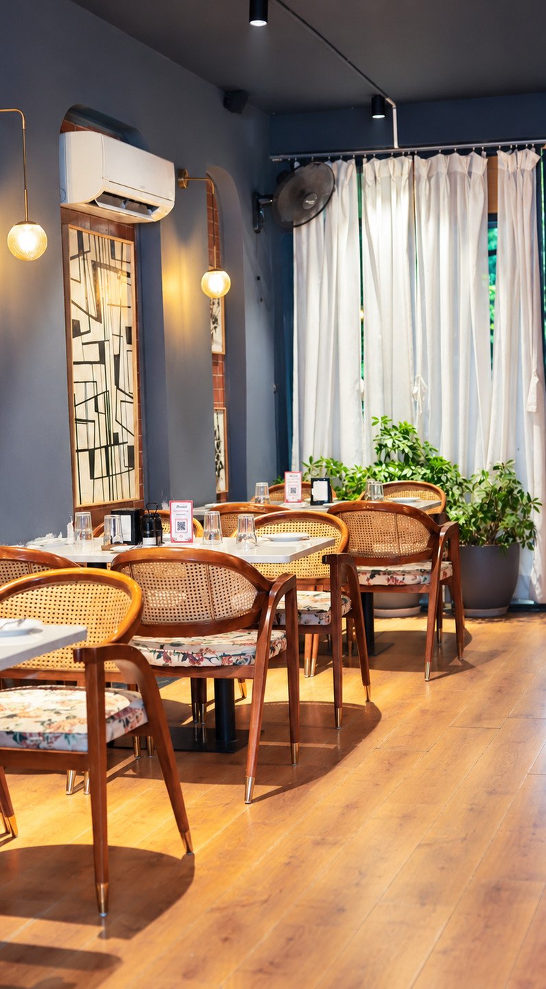 The dining room in daylight, cane chairs at white tables