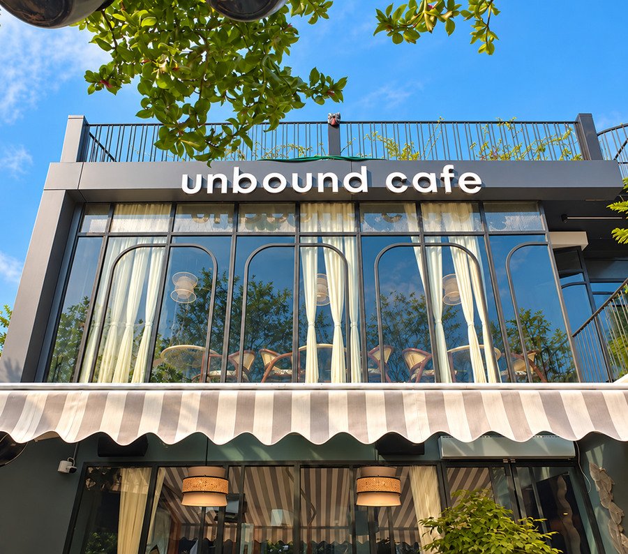 The front of UnBound by day: the sign, the arched windows and the striped awning