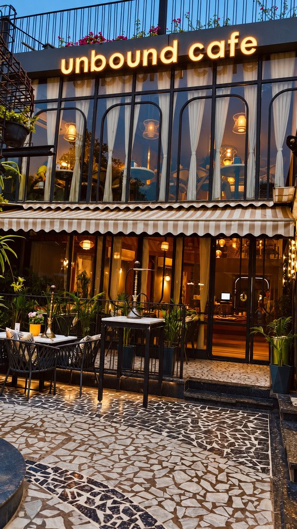 The front courtyard at dusk: mosaic floor, outdoor tables, the lit sign above