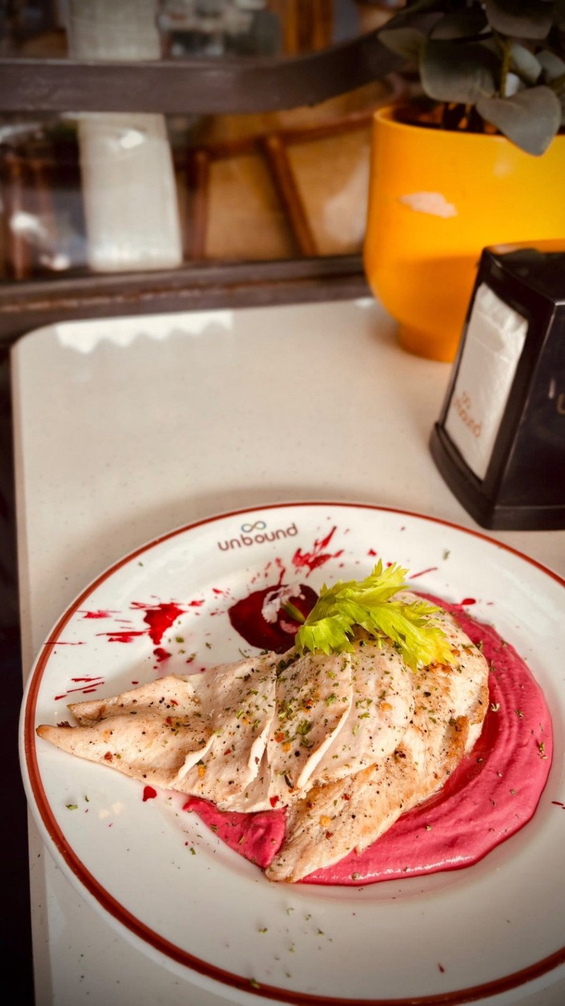 Sliced grilled chicken on a beetroot purée, on an UnBound plate