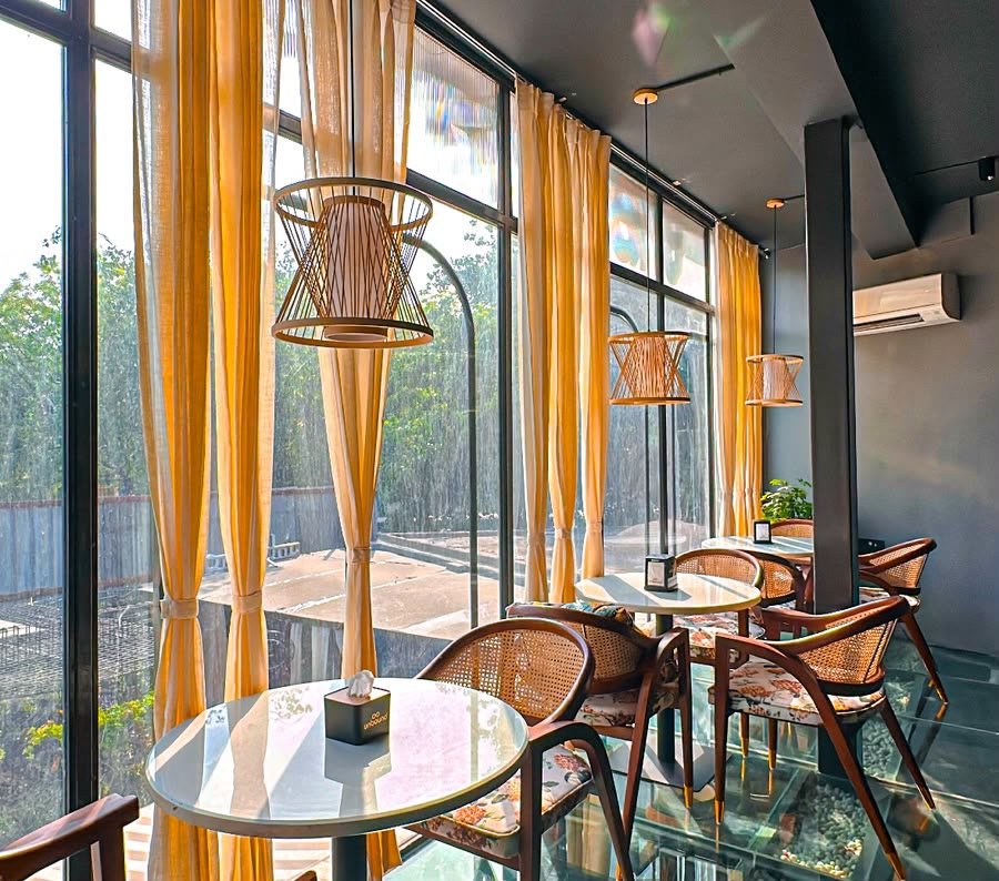 First-floor window tables in the sun, yellow curtains and cane chairs