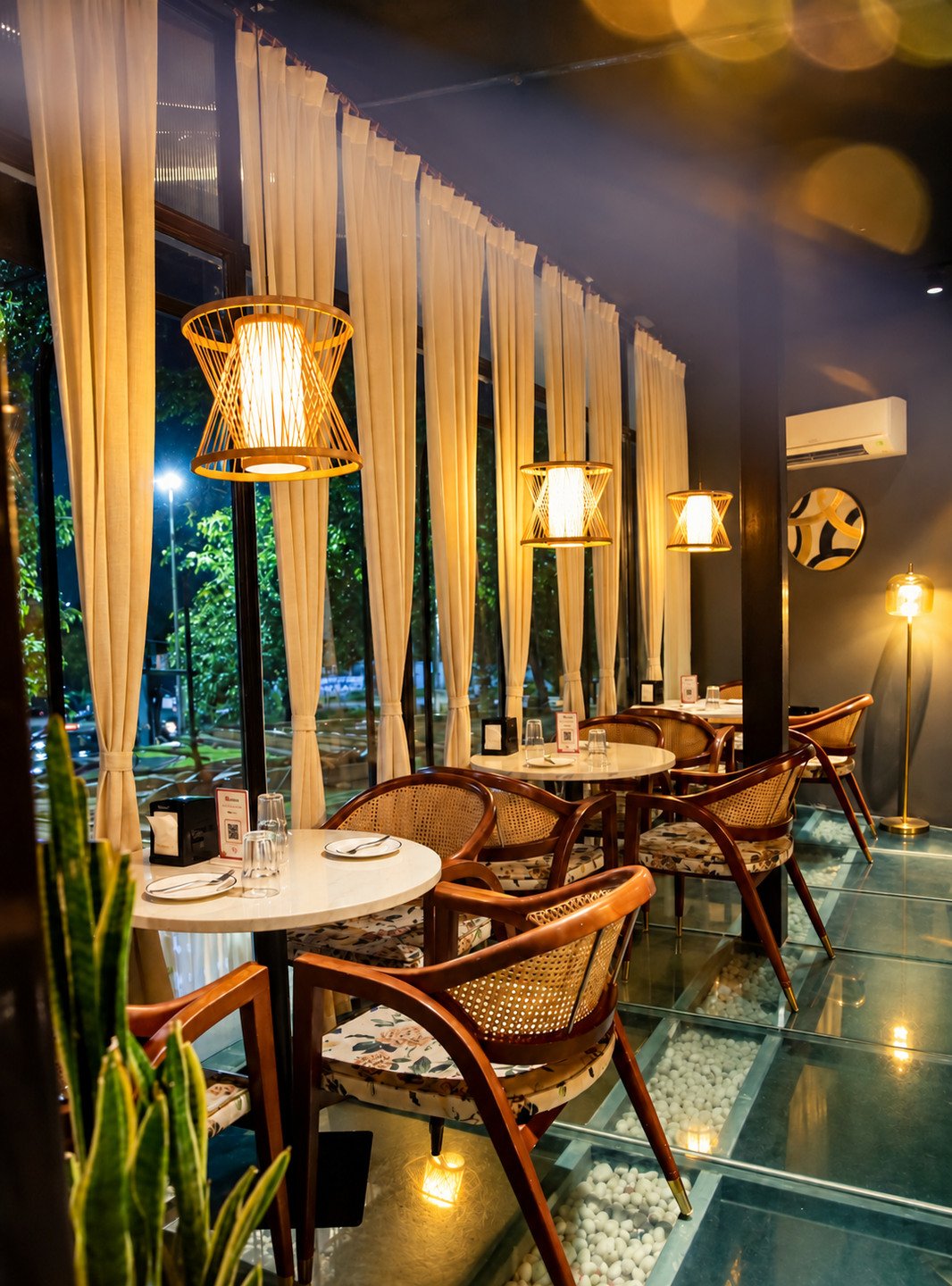 First-floor tables by the tall windows, under woven lamps